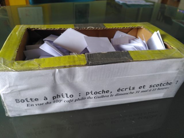 Une boîte pleine de papiers pliés, et écrit dessus : Boîte à philo : pioche, écris et scotche
